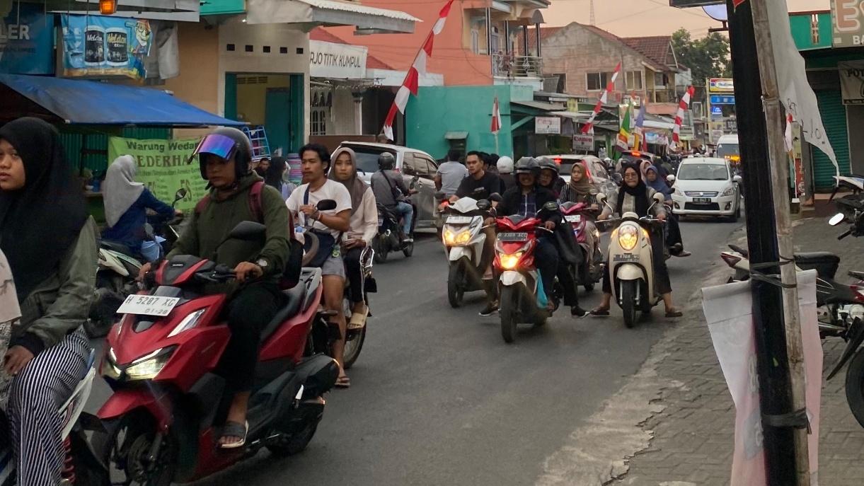 A group of people on scooters in a street

Description automatically generated
